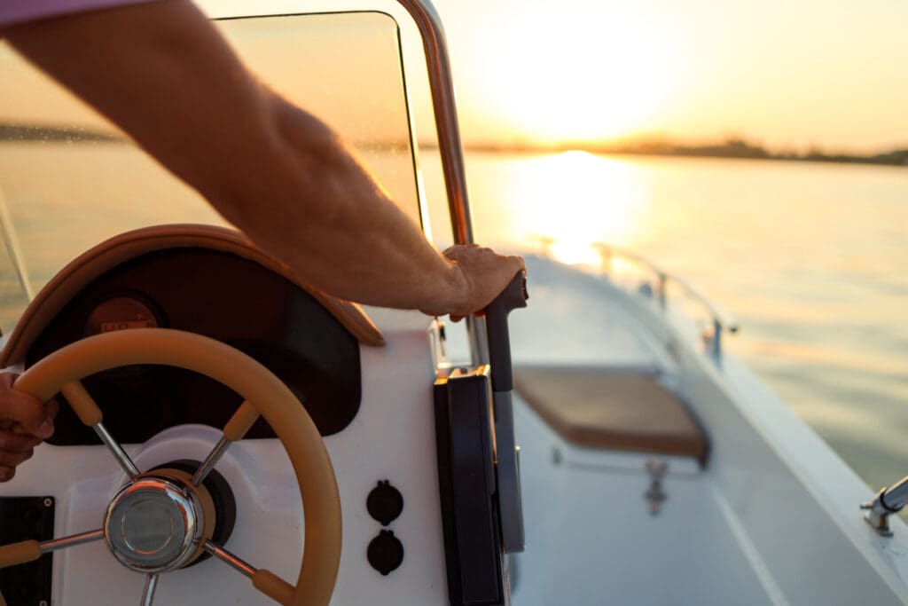 Person steering boat at sunset on water