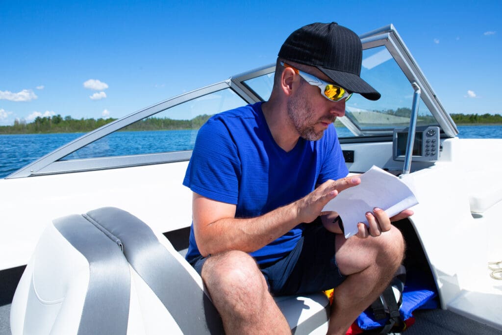 Man reading on a boat under blue sky.