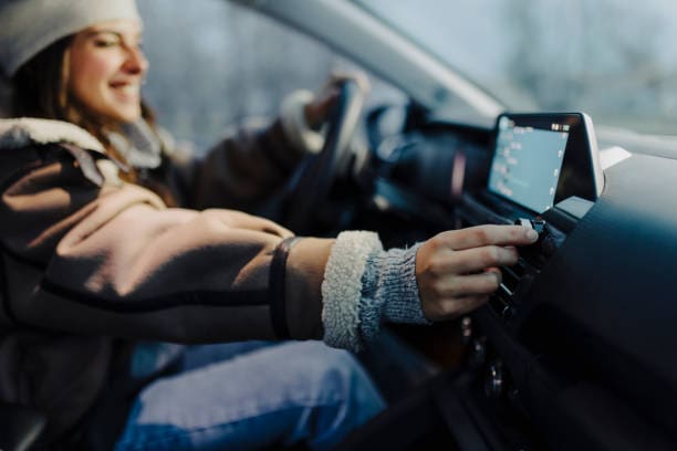 Smiling young woman using global positioning system while driving her car.