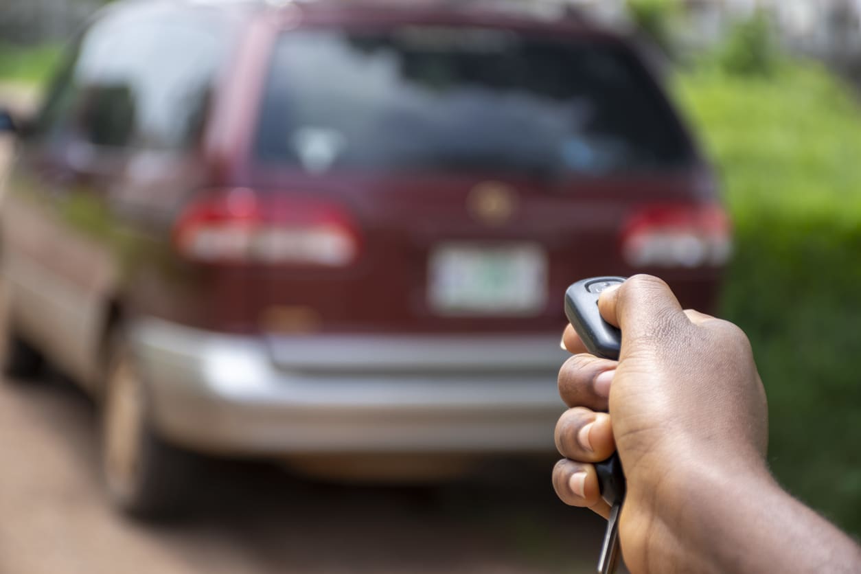 Hand holding car remote near vehicle